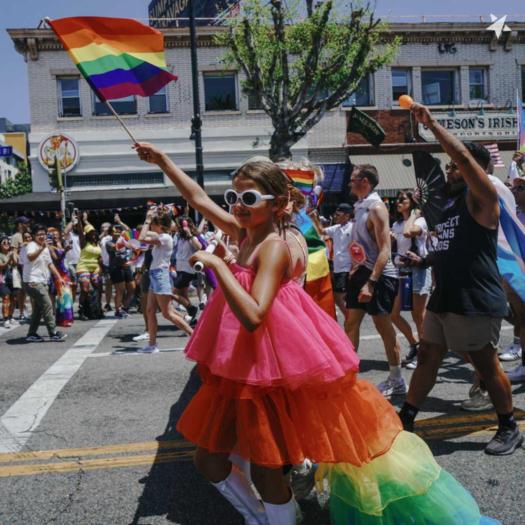 Young child waving rainbow flag during a PFLAG pride parade